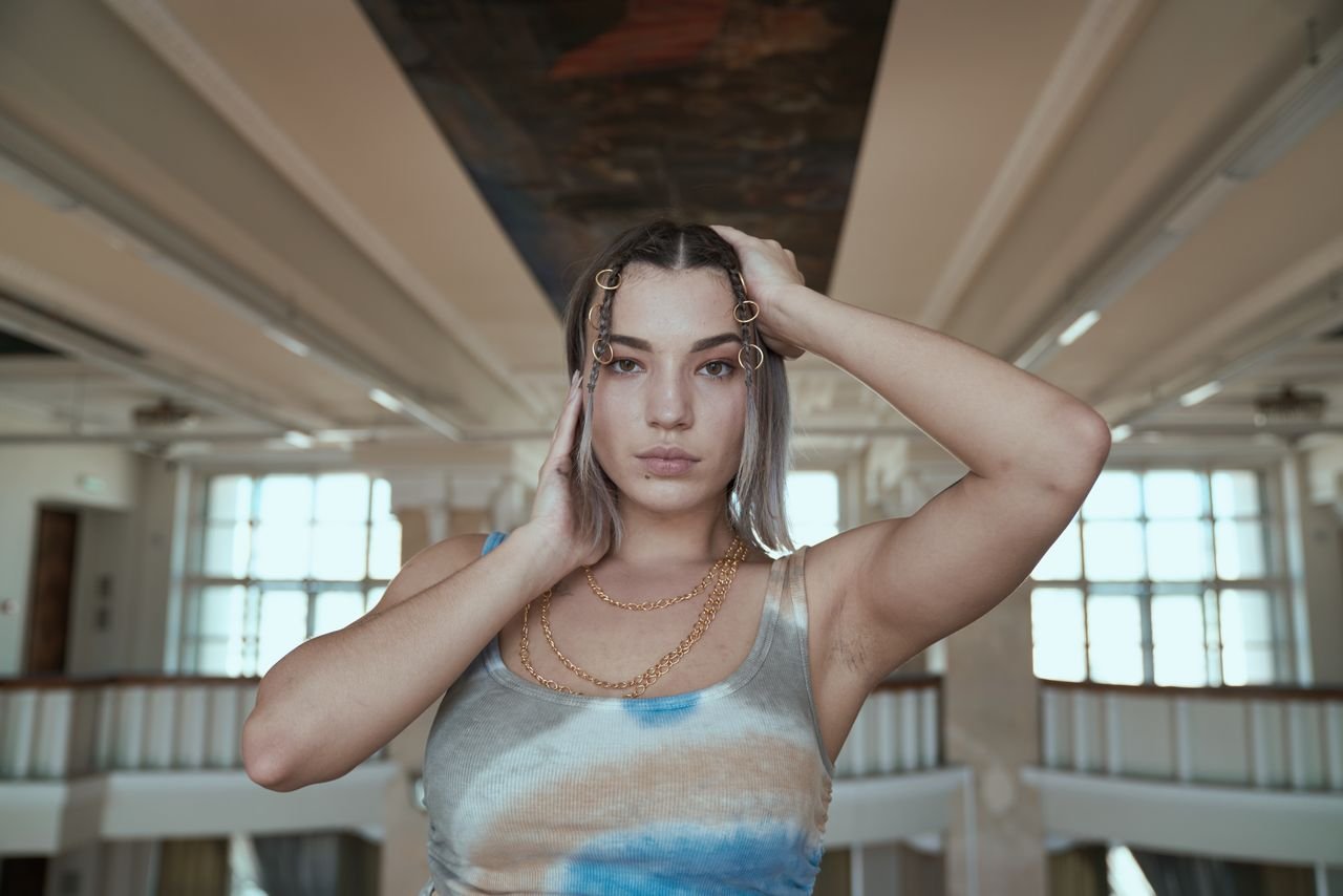 Necklaces Stylish woman in a tank top poses indoors, showcasing elegant jewelry and modern hairstyle.