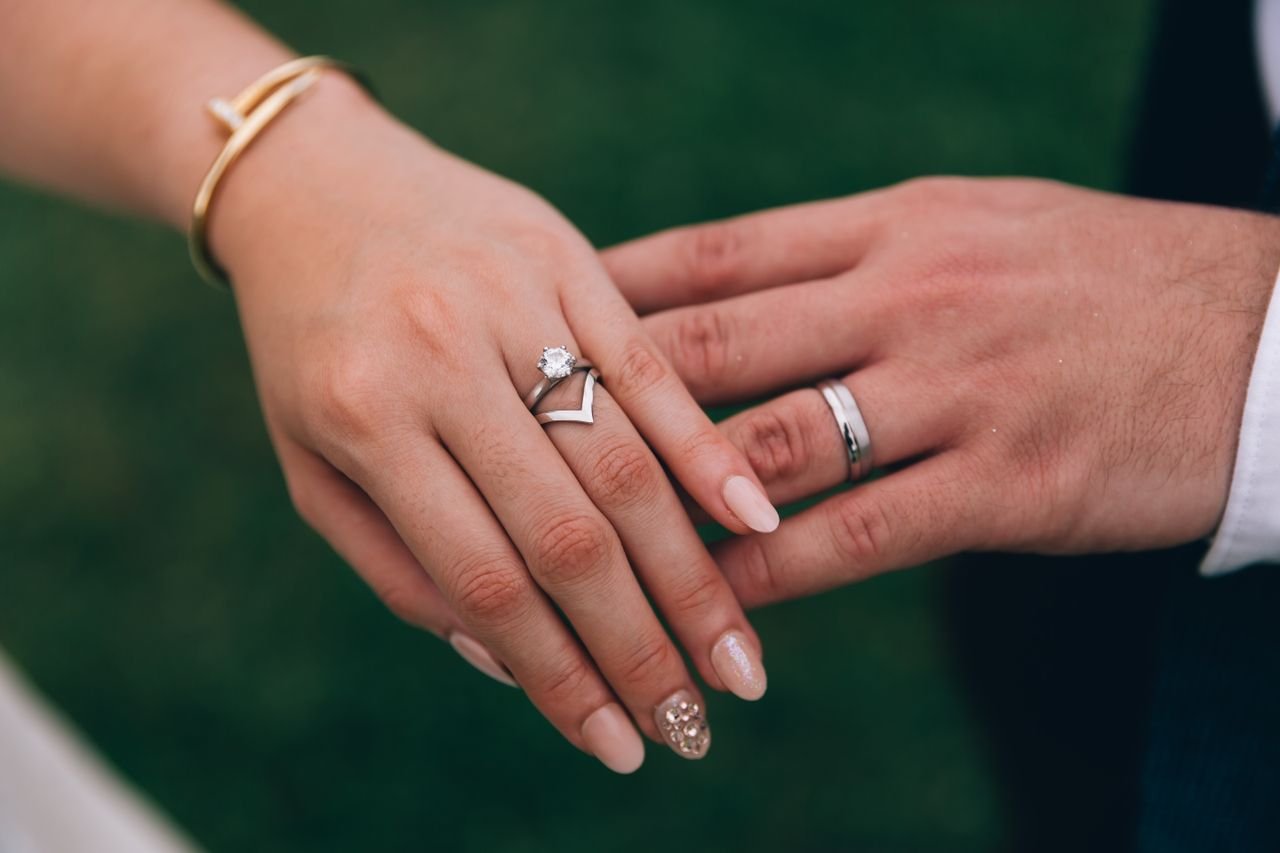 Promise Rings Intimate close-up of a couple's hands showcasing engagement and wedding rings.
