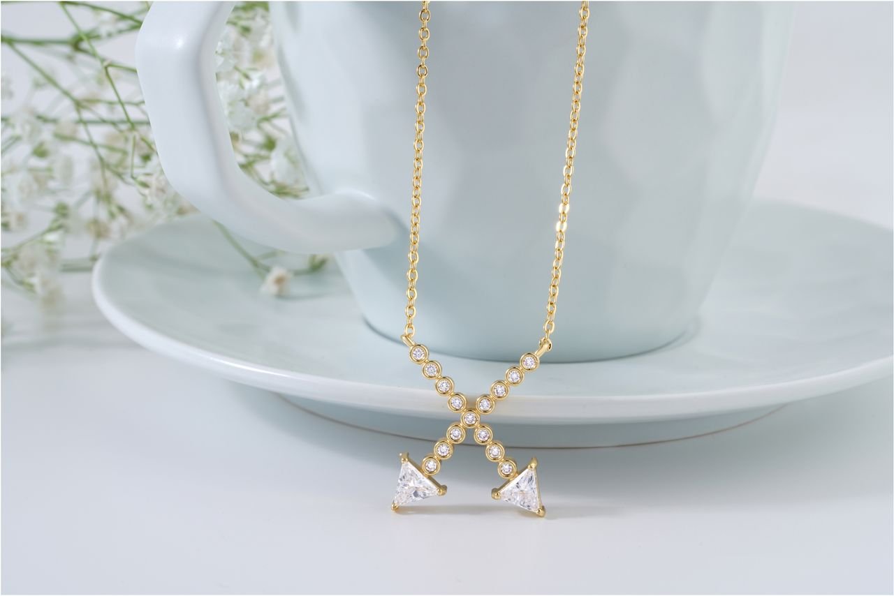 Diamond Necklaces A luxurious gold necklace adorned with diamonds elegantly draped over a ceramic cup. Perfect for jewelry enthusiasts.