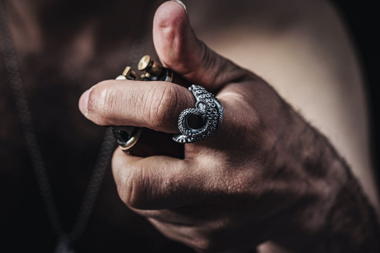 Men's Jewelry Intriguing close-up of a hand wearing an octopus-shaped ring with other jewelry pieces.