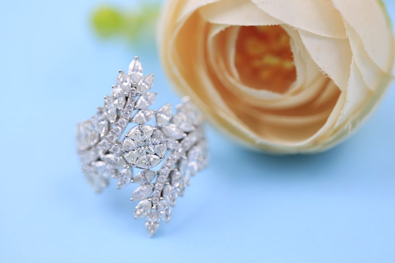 Fashion Rings Sparkling diamond ring showcased on a pastel blue background with a delicate rose, perfect for fashion and jewelry themes.