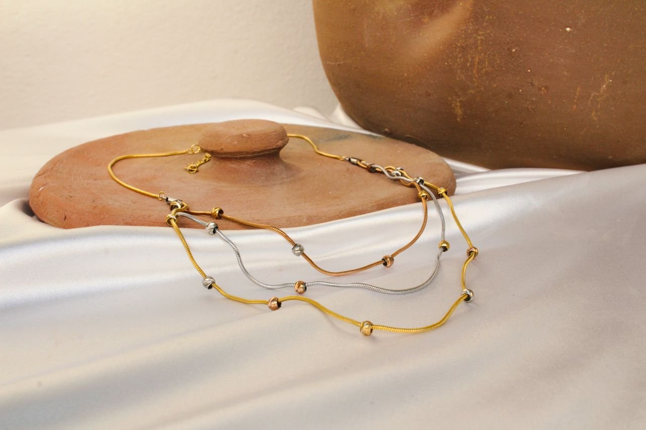 Necklaces Stylish necklaces displayed elegantly on a white fabric with a rustic clay pot backdrop.