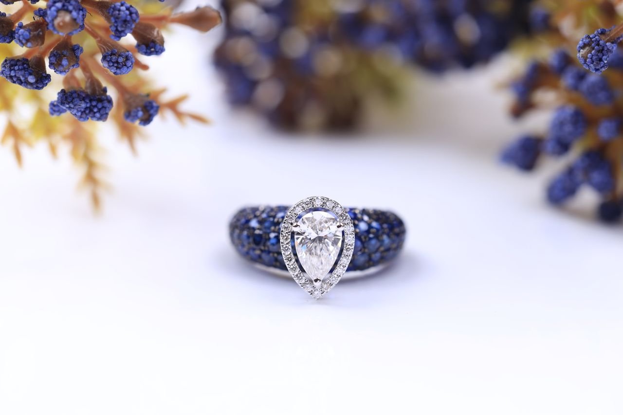 Cocktail Rings Close-up of a dazzling diamond and sapphire ring surrounded by floral elements.