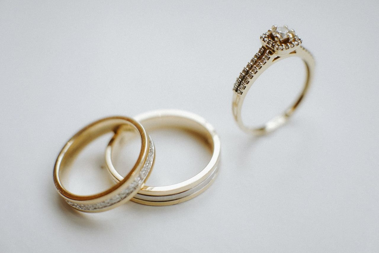 Stacking Rings Elegant gold wedding bands and a diamond engagement ring on a plain background, ideal for wedding themes.