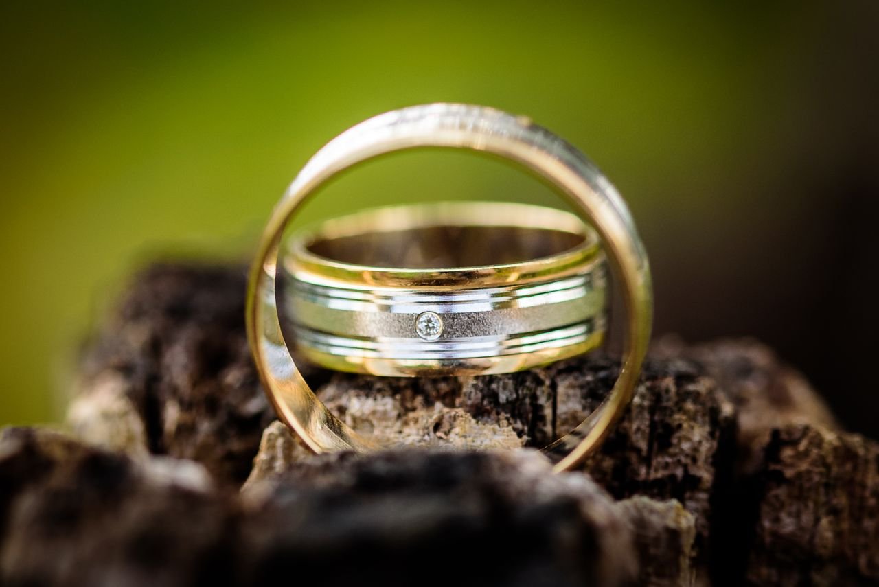 Personalized Jewelry Rustic close-up of vintage gold wedding rings with diamond on wooden background.