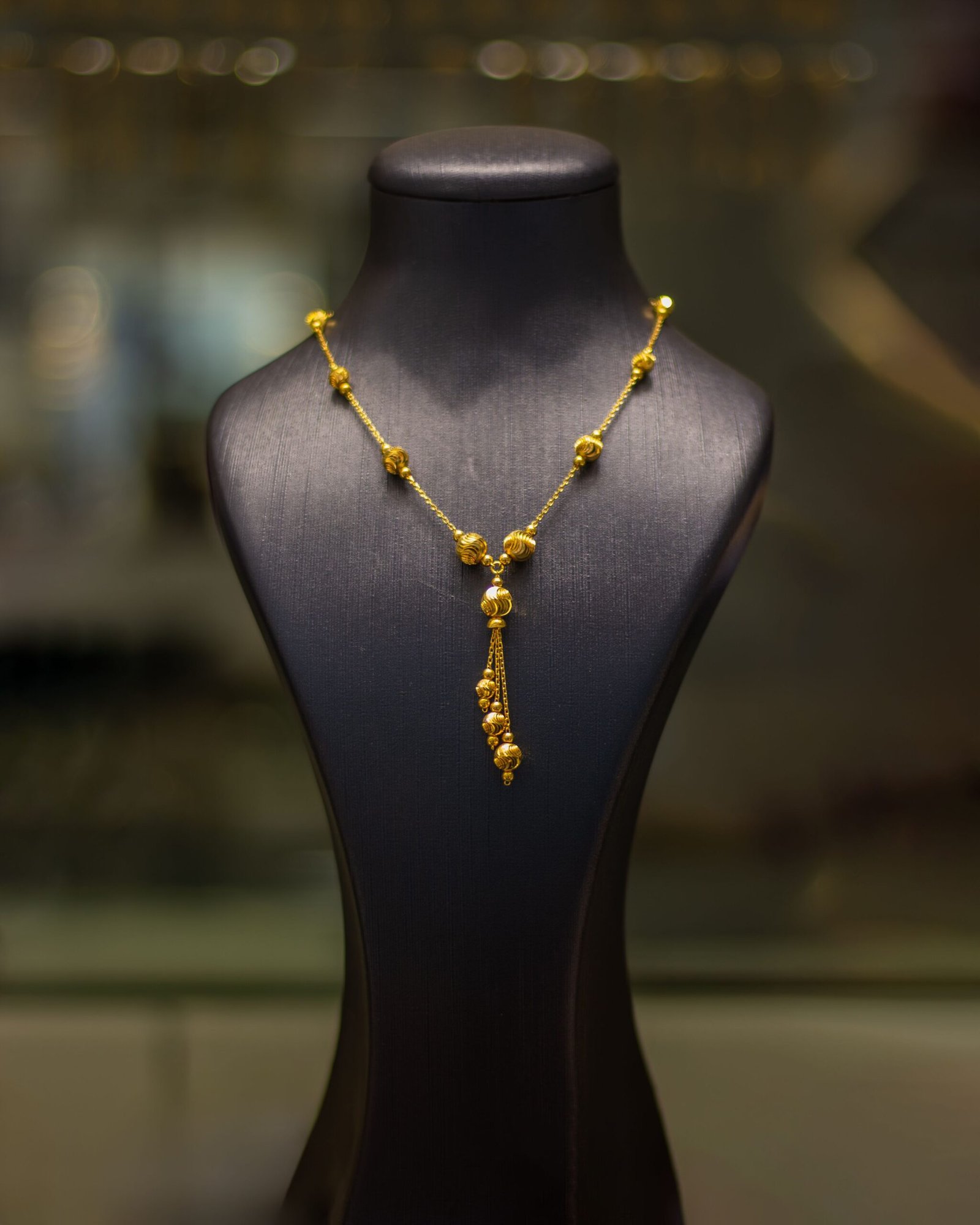 Luxurious gold necklace elegantly displayed on a black mannequin in a jewelry store.