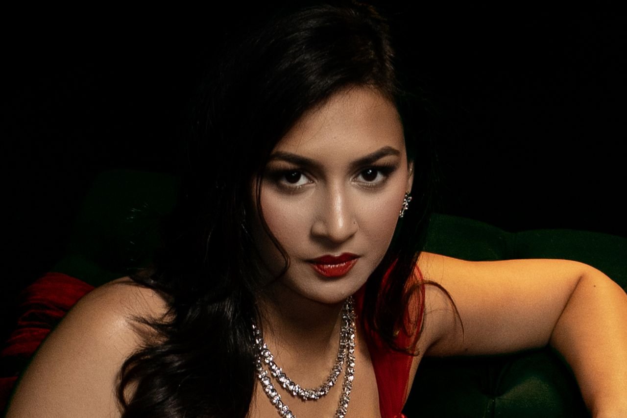 Tennis Necklaces Portrait of a woman with dark hair and red lipstick in dramatic lighting, wearing elegant jewelry.