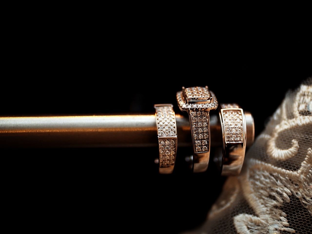 Fashion Rings Close-up of luxury diamond wedding rings elegantly arranged with delicate lace in the background.
