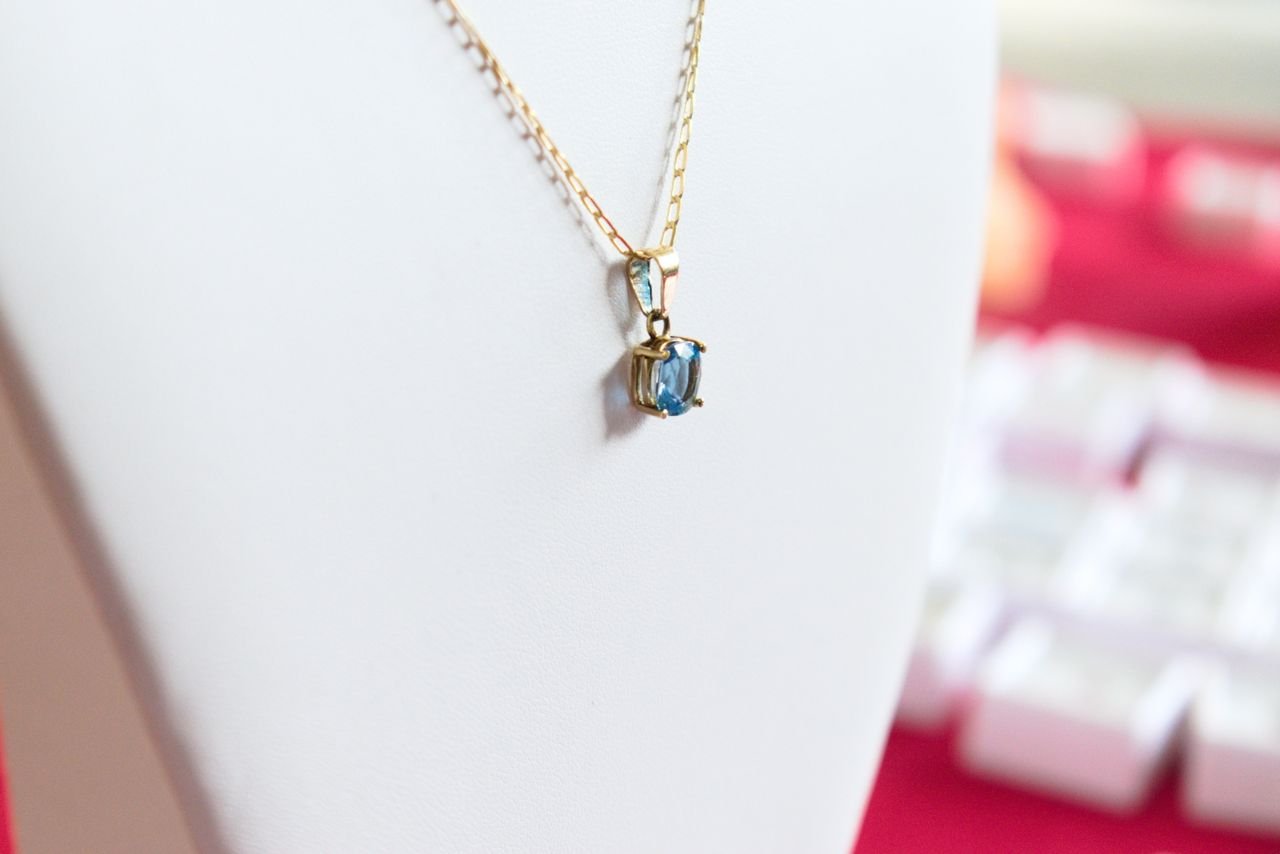 Necklaces Delicate gold necklace featuring a stunning blue gemstone pendant on display.