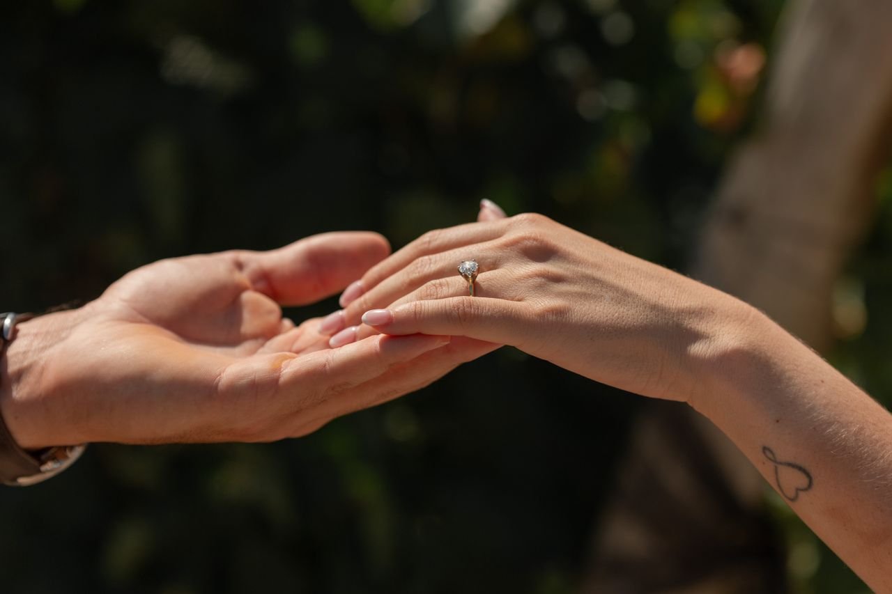 Promise Rings Close-up of hands holding, showcasing a diamond engagement ring in natural light.