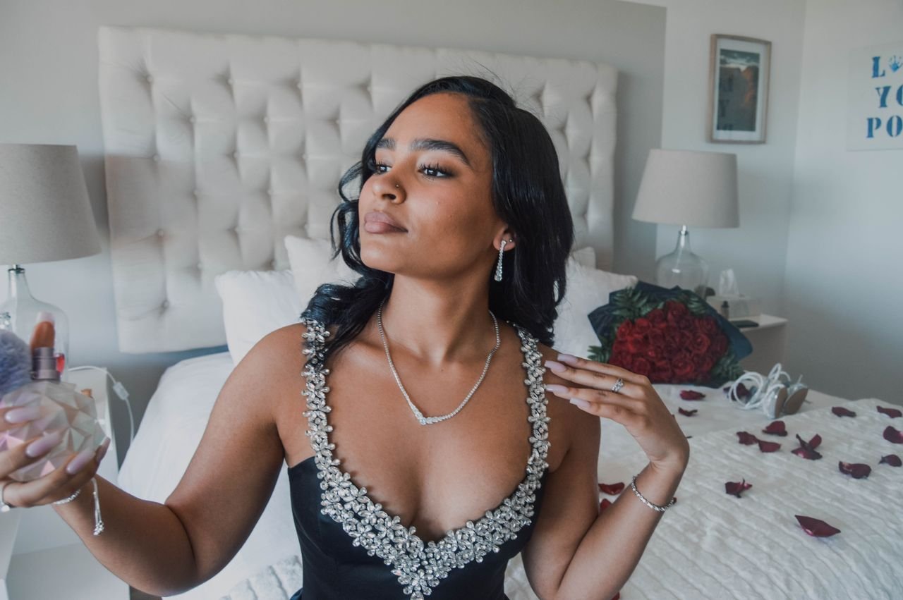 Tennis Necklaces A woman in a formal dress applies perfume, showcasing elegance and beauty indoors.