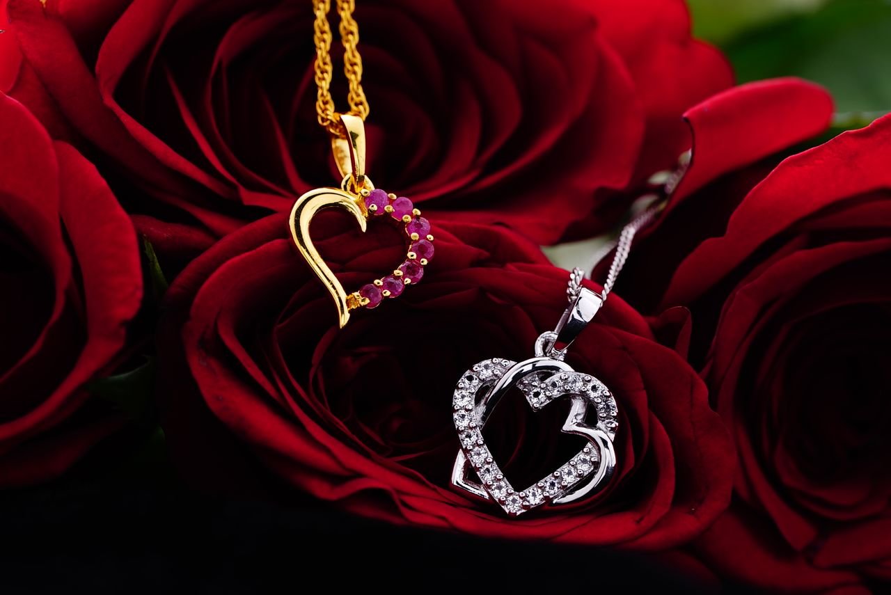 Personalized Jewelry Silver and gold decorative hearts with small gems placed on bud of red rose