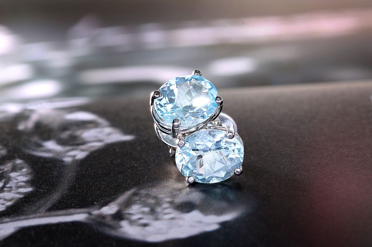 Close-up of luxurious blue topaz earrings set in white gold, showcasing their dazzling oval cut and brilliance.