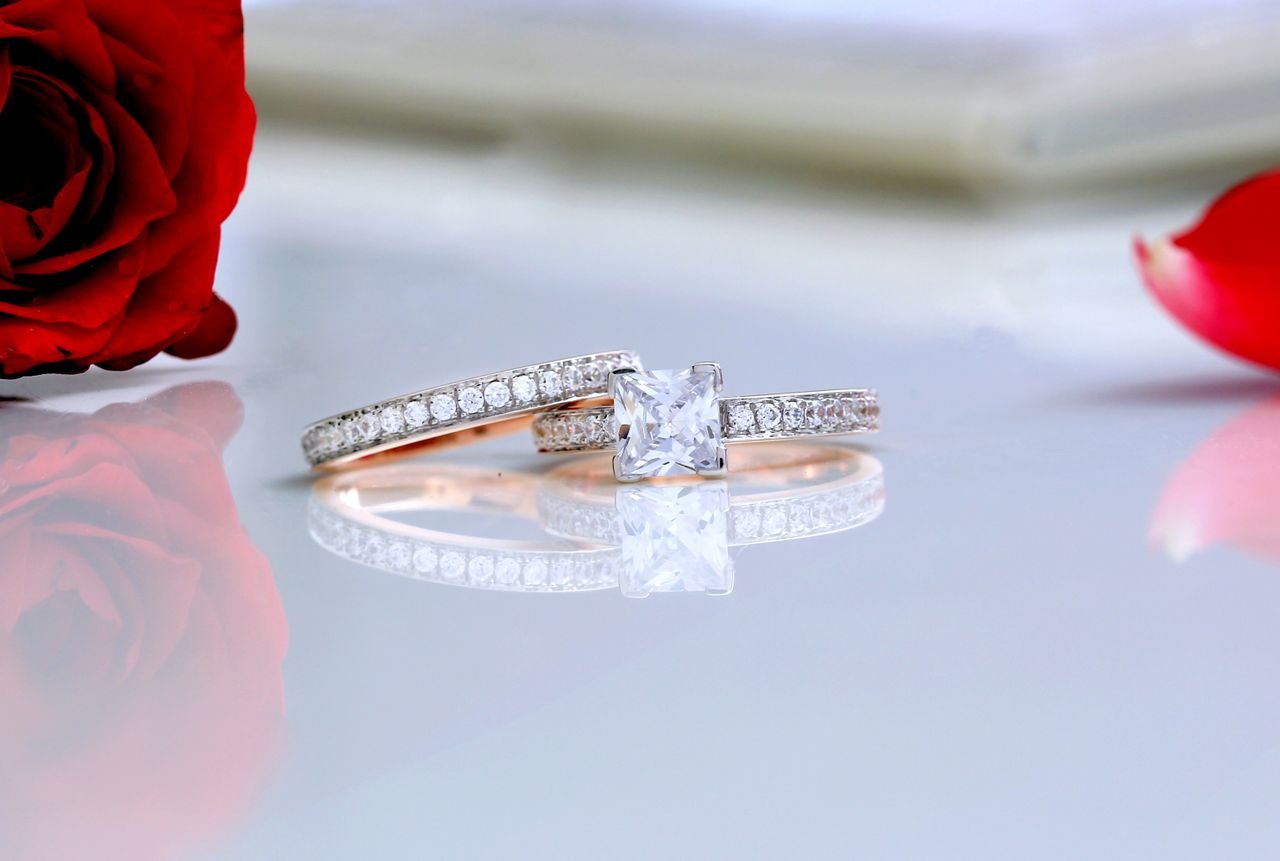 Stacking Rings Close-up of diamond silver rings with red roses, perfect for weddings and romance themes.