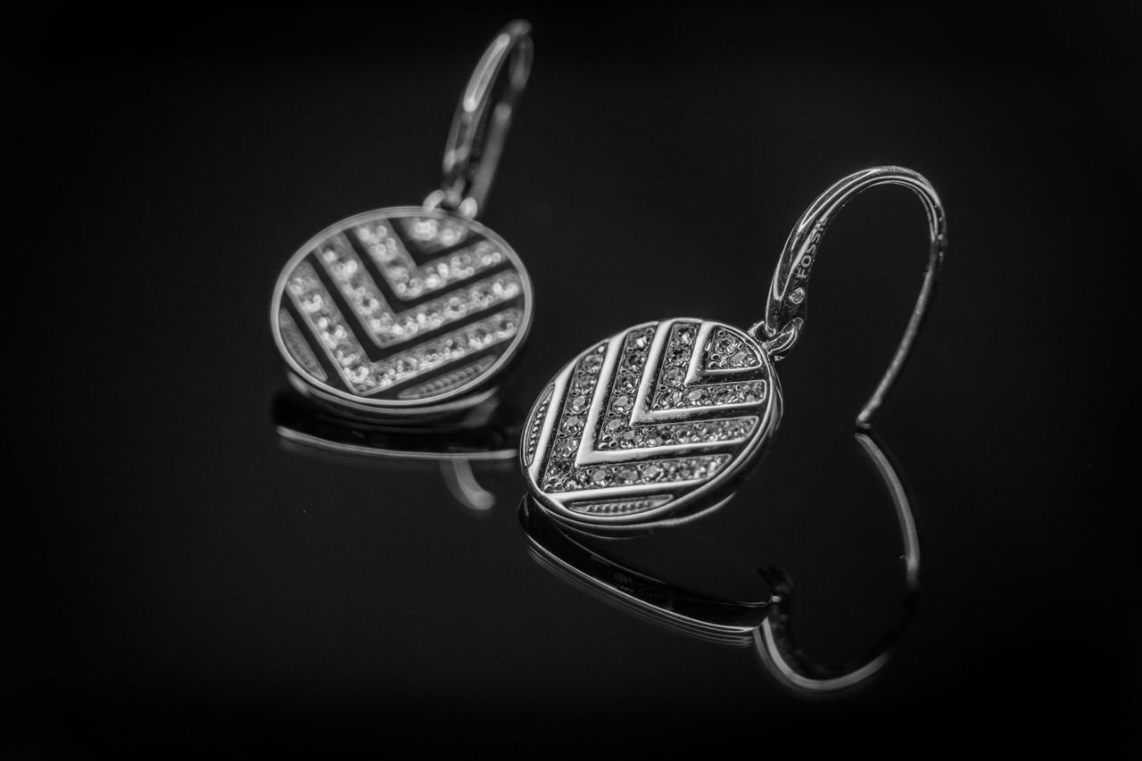 Close-up of luxurious diamond earrings with intricate design on a black background.