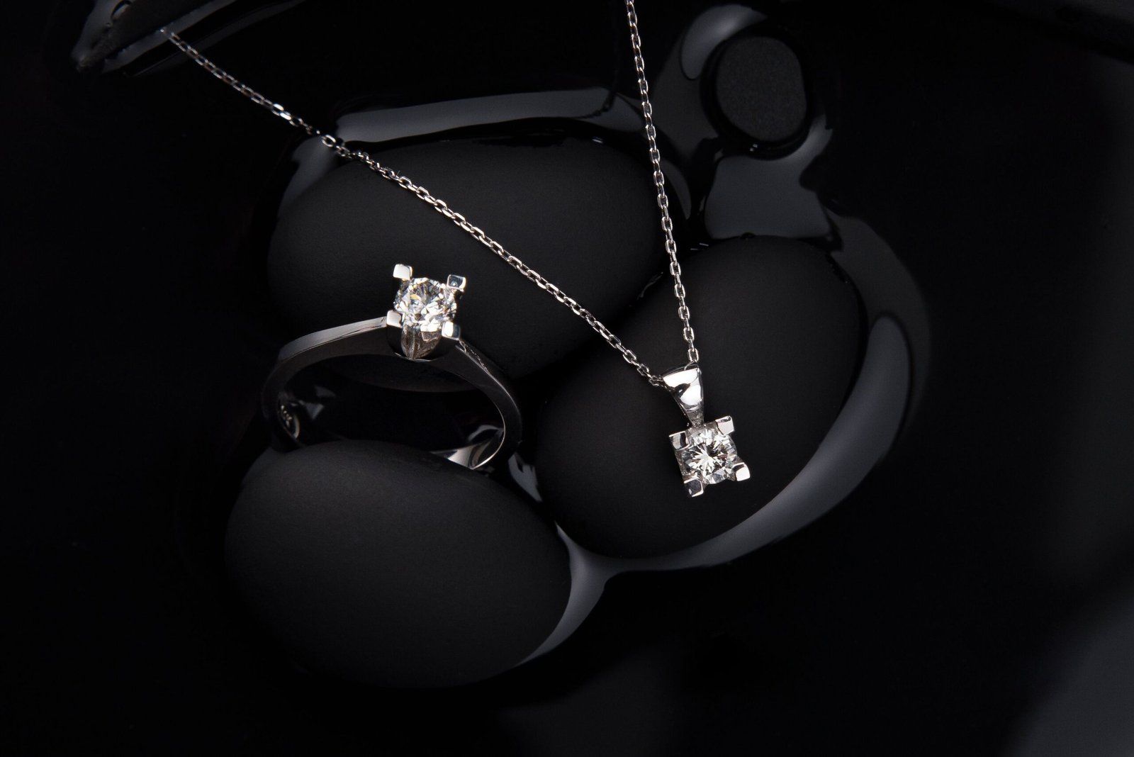Home Luxurious silver diamond ring and pendant necklace on a black background, showcasing elegance and sophistication.