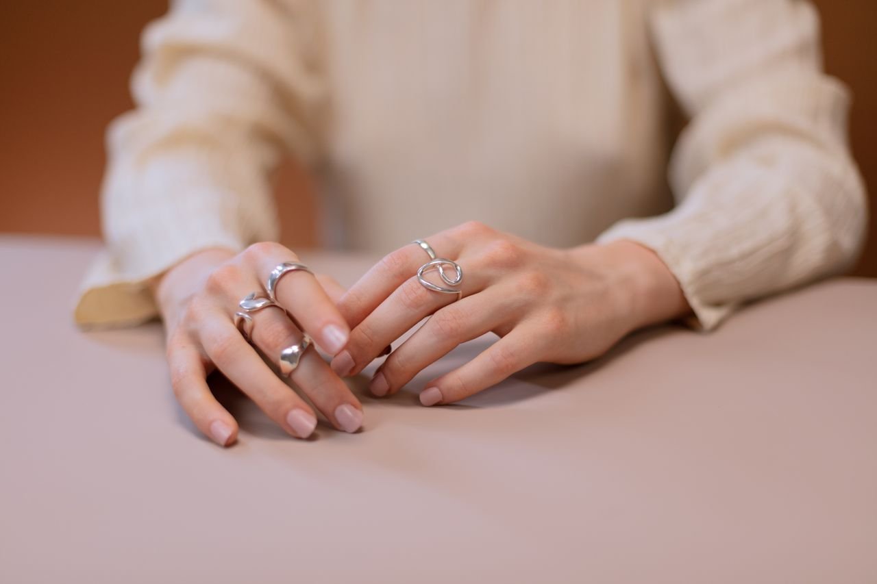 Fashion Rings Close-up of hands adorned with stylish silver rings, showcasing modern jewelry design on a subtle background.